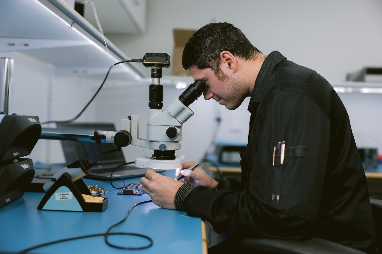 Aversan employee inspecting something with a microscope